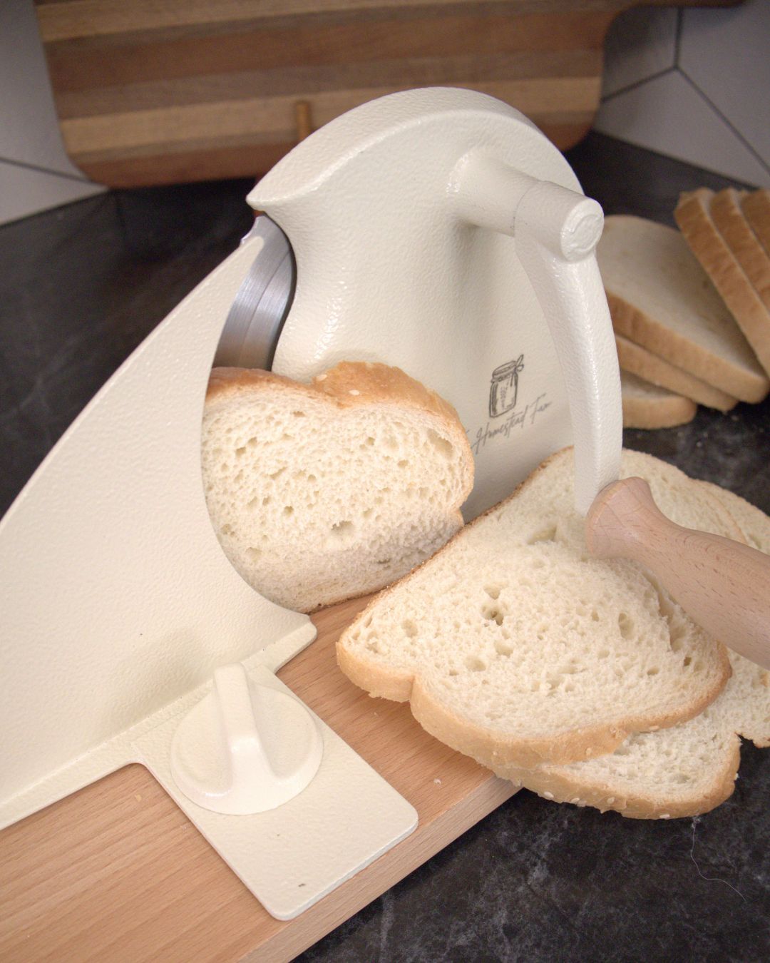 Bread slicer cutting slices of bread on a wooden board with a kitchen background.